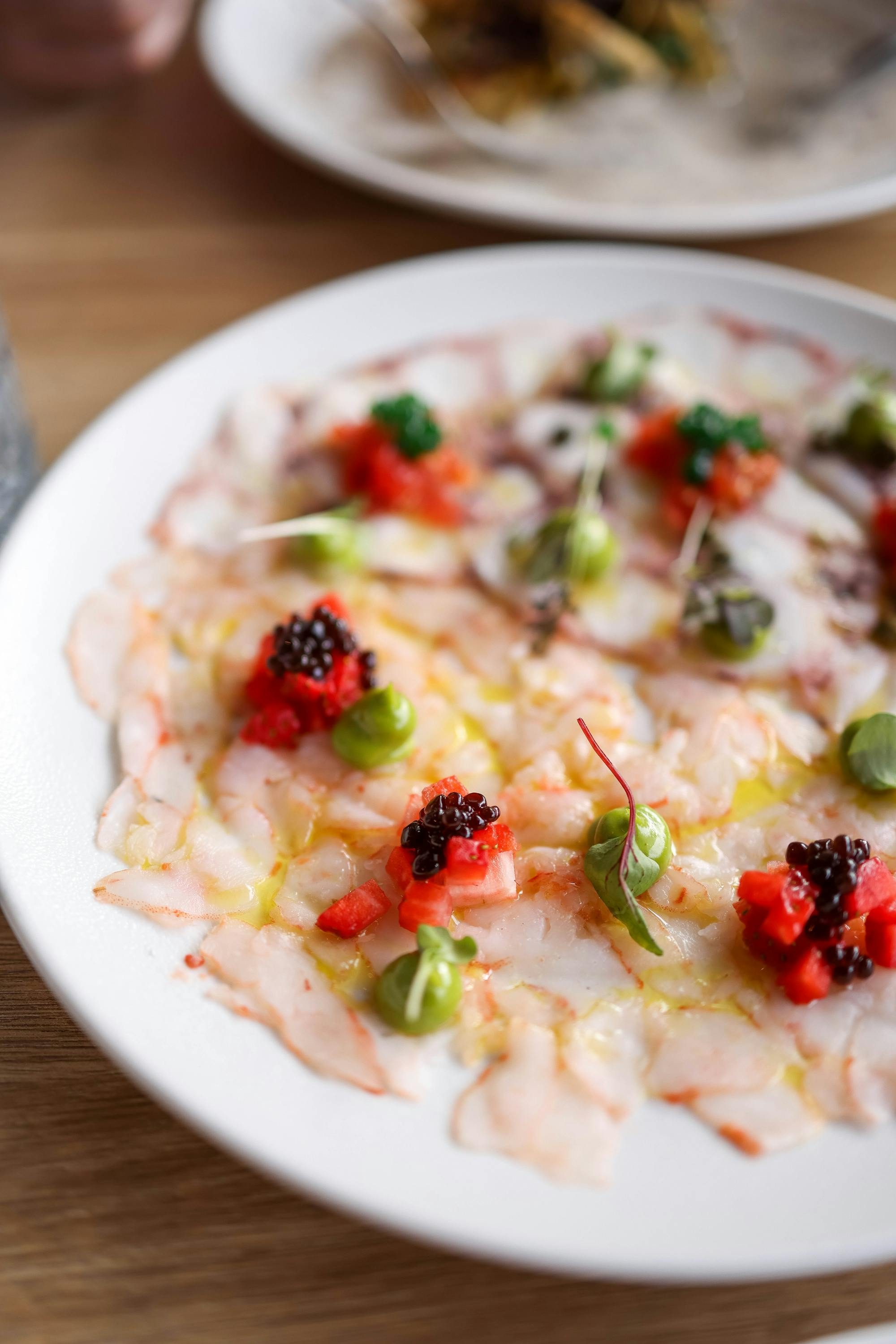 Carpaccio di branzino — Tagliato sottile, lime, olio del Garda, pepe rosa, fiori di nasturzio.